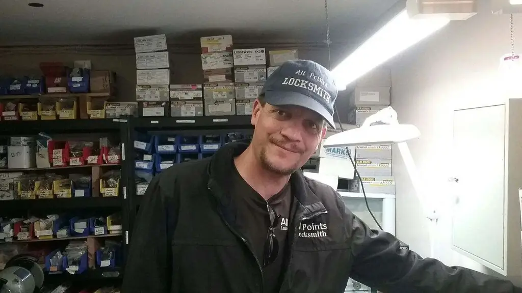 A smiling technician in an All Points uniform standing in the shop's parts room